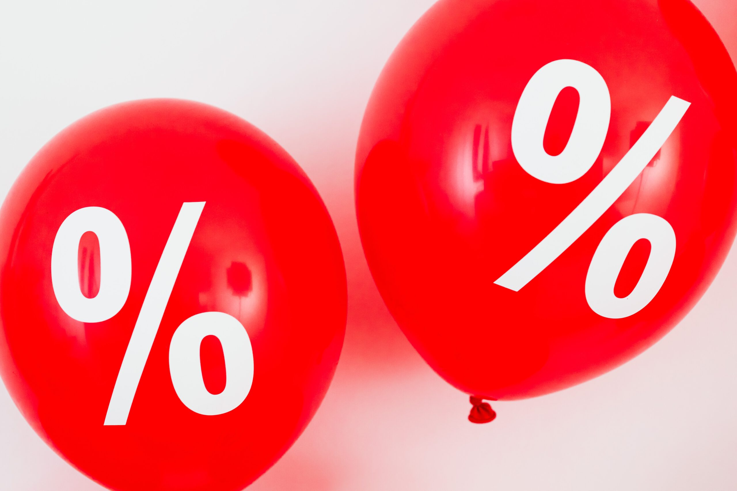 Dwa czerwone balony z białymi nadrukami znaku procentu