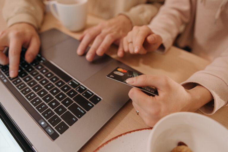 Dwie osoby z kartą płatniczą w ręce pracujące na laptopie