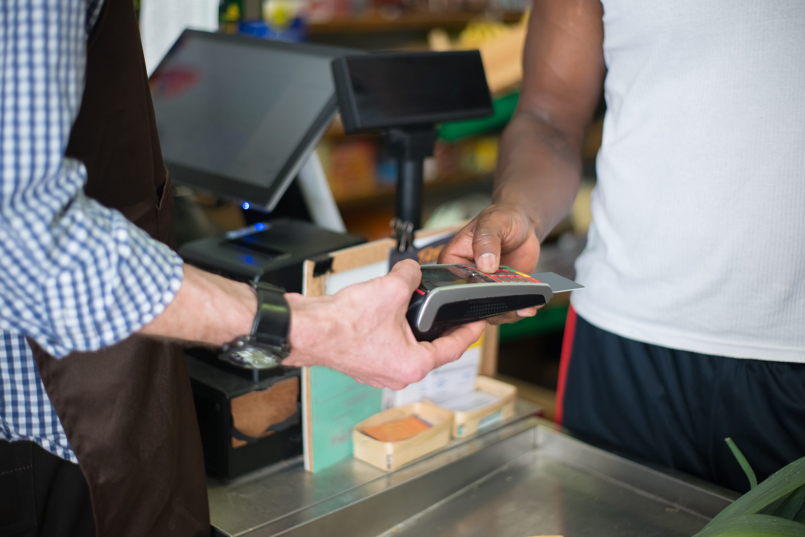 Mężczyzna wkładający kartę kredytową do terminala płatniczego