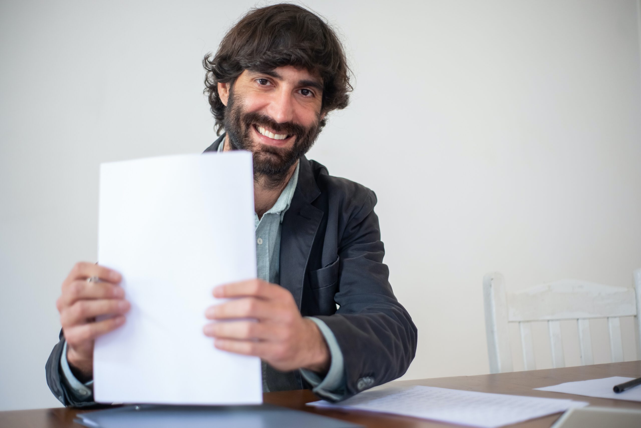 Uśmiechnięty mężczyzna za biurkiem trzymający dokumenty